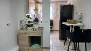 Een compacte keuken met een eethoek, met een houten kast, een tafeltje en een zwarte stoel.