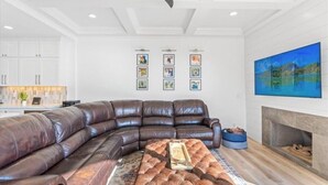 Ein modernes Wohnzimmer mit einer großen, L-förmigen Couch, einem Kamin und gerahmten Kunstwerken an der Wand.