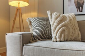 A sofa with a zebra-patterned pillow and a fluffy white throw blanket. - Cosy & Stylish Edinburgh City Flat - Pass the Keys (Edinburgh)
