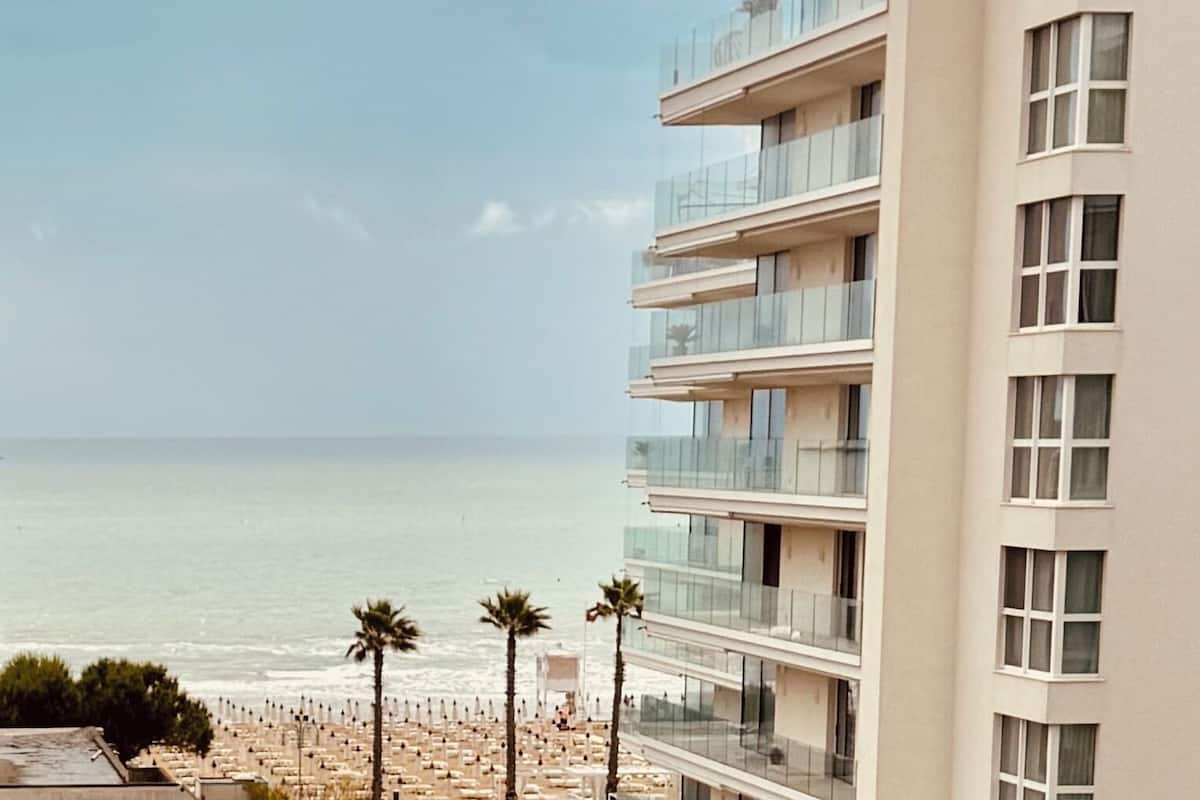 A modern hotel with multiple balconies overlooking a beach.