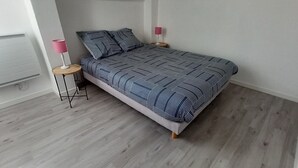 Een slaapkamer met een bed, twee nachtkastjes, een lamp en een wandradiator.