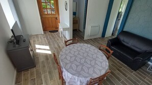 Een eetgedeelte met een ronde tafel, stoelen en een zwarte leren bank.