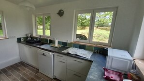 Een compacte keuken met een vaatwasser, een spoelbak en een raam met uitzicht op een tuin.