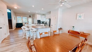 A spacious kitchen with white cabinets, a central island, and a dining area with wooden chairs and a table. - This one's for David 3 bed 2.5 bath home with POOL (North Topsail Beach)