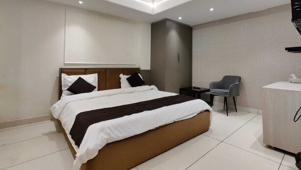 A modern hotel room with a large bed, a desk, and a chair. - Hotel M.K (Pathankot)