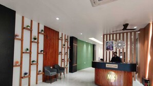 A reception area with a wooden reception desk, two chairs, and a green wall. - Hotel M.K (Pathankot)