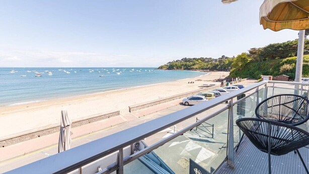A balcony with a view of a beach and the sea.