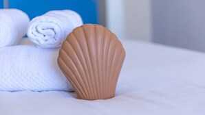 A bed with white linens and a brown decorative object resembling a seashell. - Au pied de la plage 1 - Vue mer (Cancale)