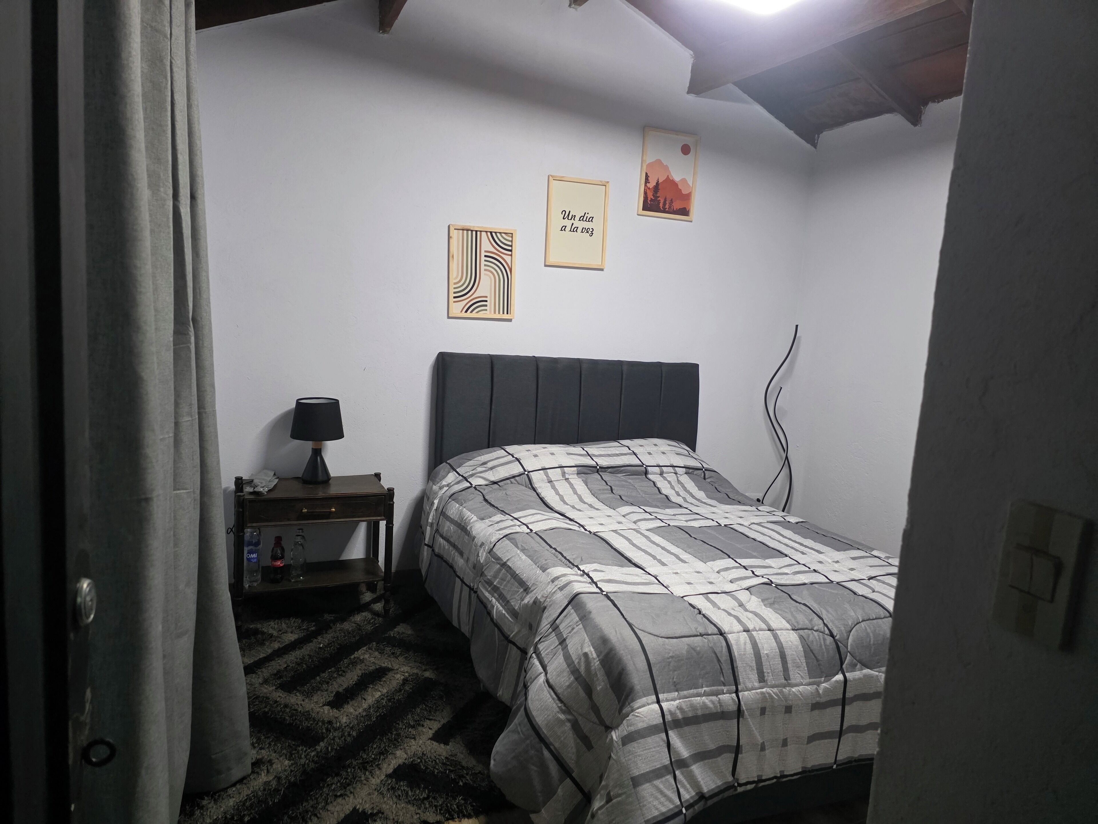 Une chambre à coucher comprenant un lit, une table de chevet, une lampe et deux œuvres d’art murales.