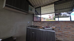 A compact kitchen with a gas stove, sink, and a window overlooking a residential area.