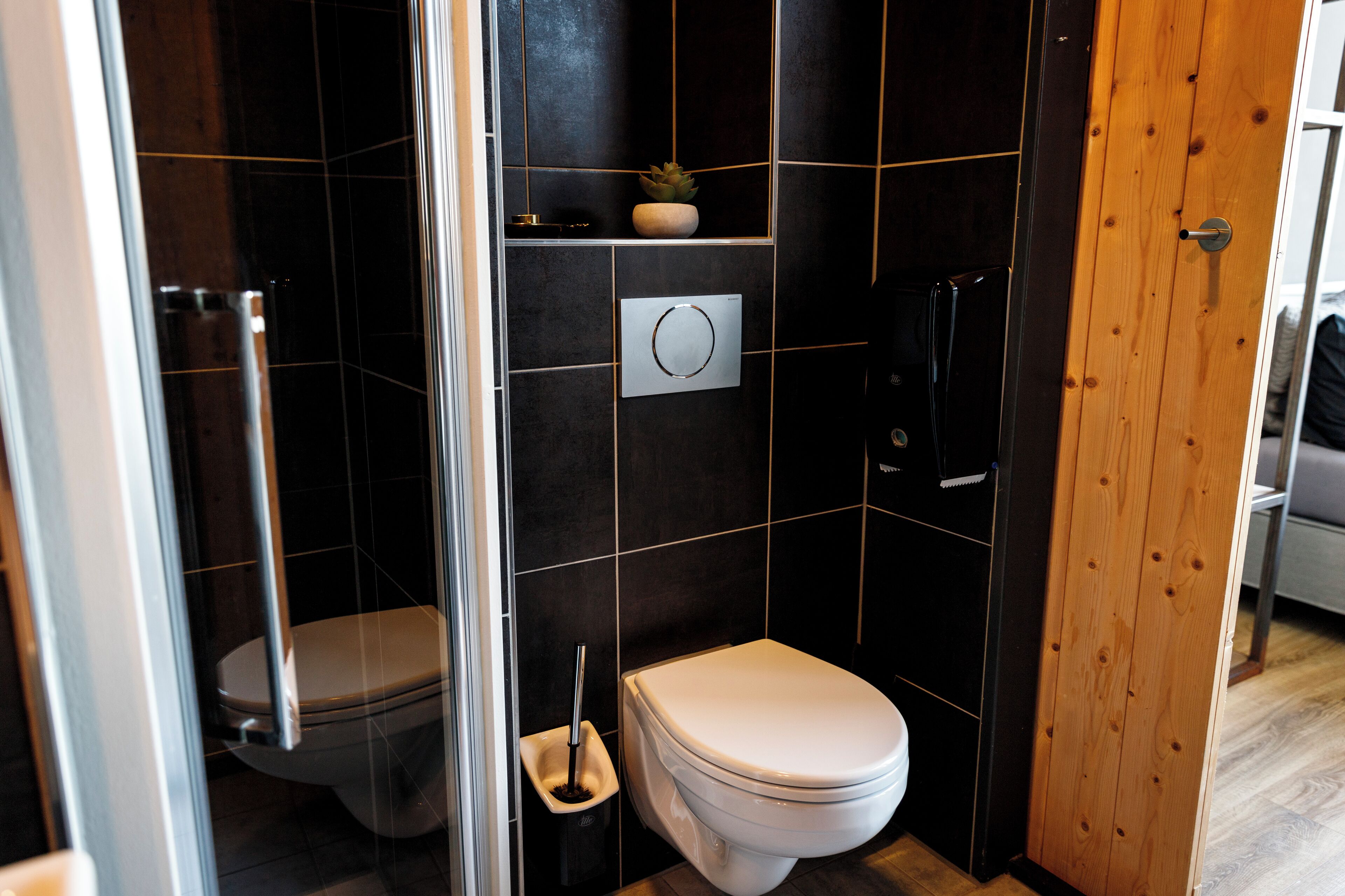 A modern bathroom with a toilet, bidet, and a glass shower enclosure.