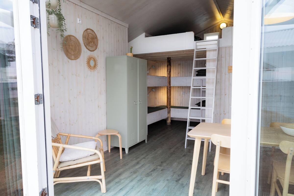 A compact room with bunk beds, a wardrobe, a small table, and a chair.