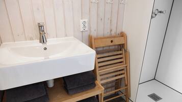 Ein Badezimmer mit einem weißen Waschbecken, einem hölzernen Handtuchhalter und einer Duschkabine.