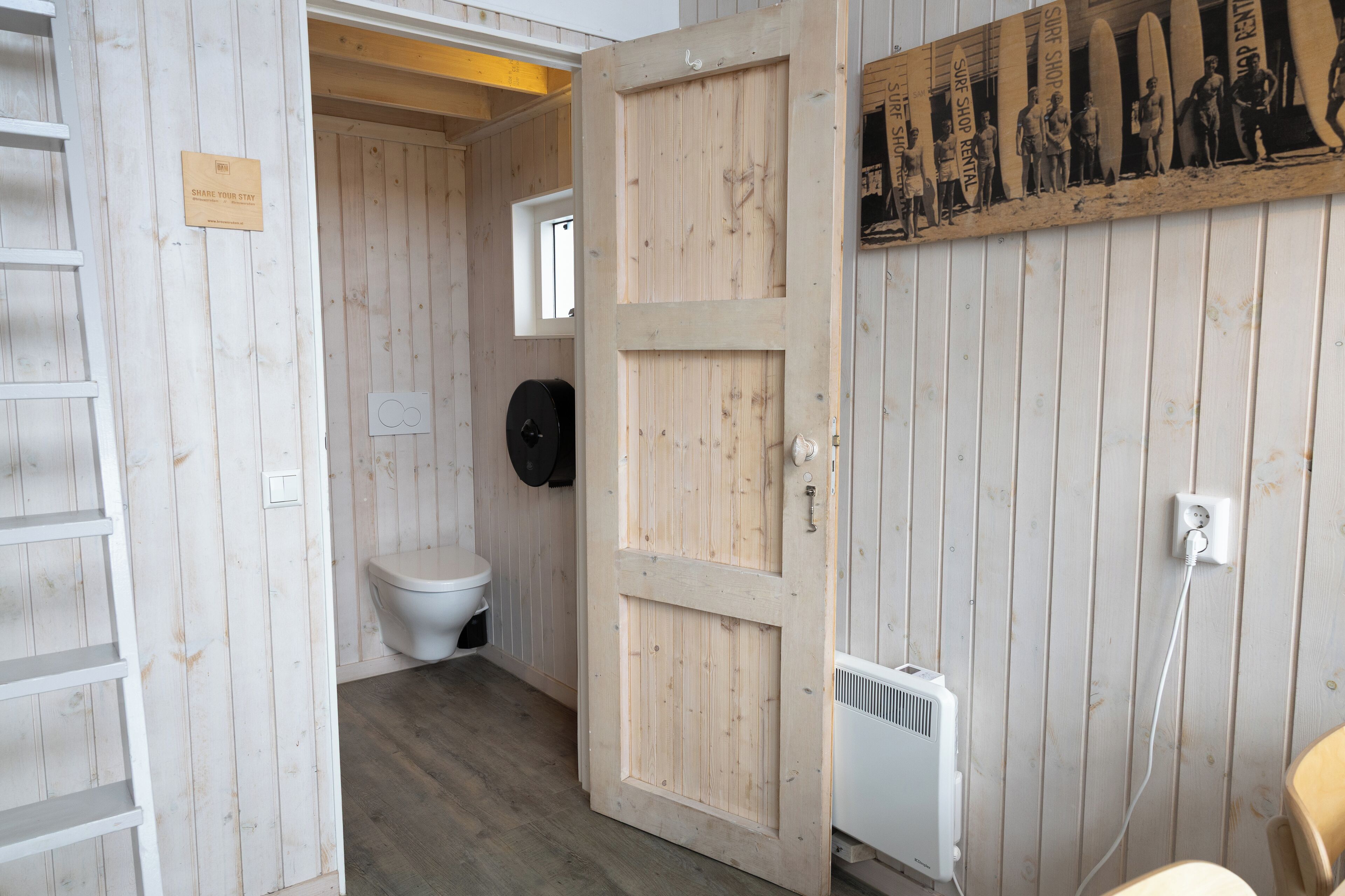 Ein Holzeinrichtung mit Toilette, einer Tür und einem Wandheizgerät.