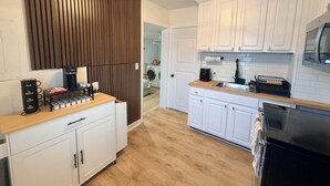 Una cocina moderna con armarios blancos, encimera de madera y microondas integrado.