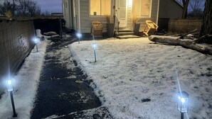 Una casa con un camino de entrada cubierto de nieve y un porche delantero.