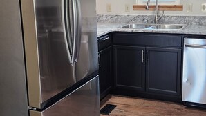 A kitchen with a stainless steel refrigerator, black cabinets, a window, and a wooden floor. - 3324 Barbury LN, 37931 (Knoxville)