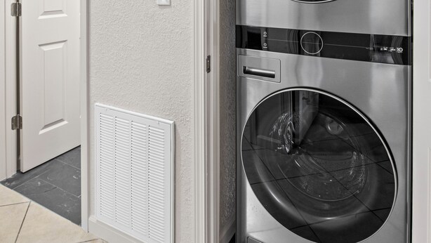 A laundry room with two stacked front-loading washing machines, a white door, a wall-mounted thermostat, and a ceiling-mounted smoke detector. - 3324 Barbury LN, 37931 (Knoxville)