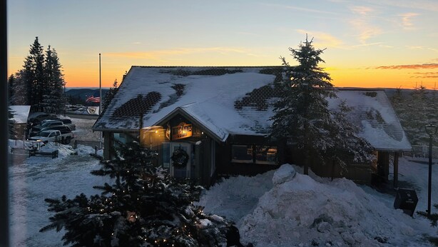 A snow-covered building with a visible American flag, surrounded by snow-laden trees and a clear sky. - Ski-In + Out XL Studio. Expedition Station in Village. Mtn Views. 2 Queen Beds. (Snowshoe)