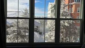 A window with a view of snow-covered trees and buildings. - Ski-In + Out XL Studio. Expedition Station in Village. Mtn Views. 2 Queen Beds. (Snowshoe)