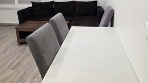Moderni olohuone, jossa on valkoinen sohva, harmaat nojatuolit ja valkoinen pöytä.