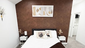 Un dormitorio con cama, una banca, ventilador de techo y una obra de arte en la pared.