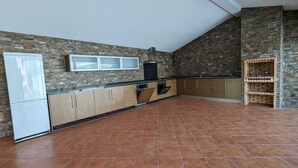 Una cocina con protector mural de piedra, armarios de madera, horno empotrado y piso de baldosas.