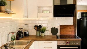 Una cocina moderna con armarios blancos, encimera de madera, estufa integrada y campana extractora negra.