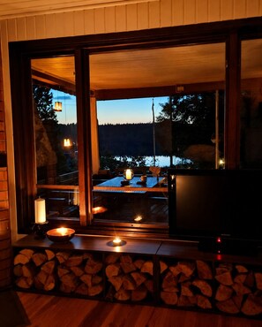 A cozy room with a large window, a television, and a fireplace. - Swedish Magic – An Exclusive Retreat by the Lake with a Private Dock, Boat, and Guest House (Belganet)