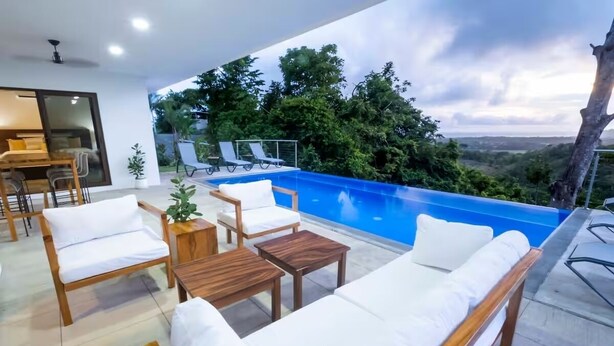 Ein moderner Poolbereich im Freien mit Liegestühlen und einer Essgelegenheit.