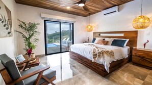 Ein modernes Schlafzimmer mit einem großen Bett, Holzboden und Blick auf einen Swimmingpool.