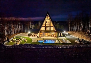 A triangular-shaped building with a swimming pool, outdoor seating, and a well-lit interior. - Private Heated Pool, Hot Tub & Game Room Getaway (Hot Springs)