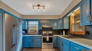 A kitchen with blue cabinets, stainless steel appliances, and a wooden countertop.