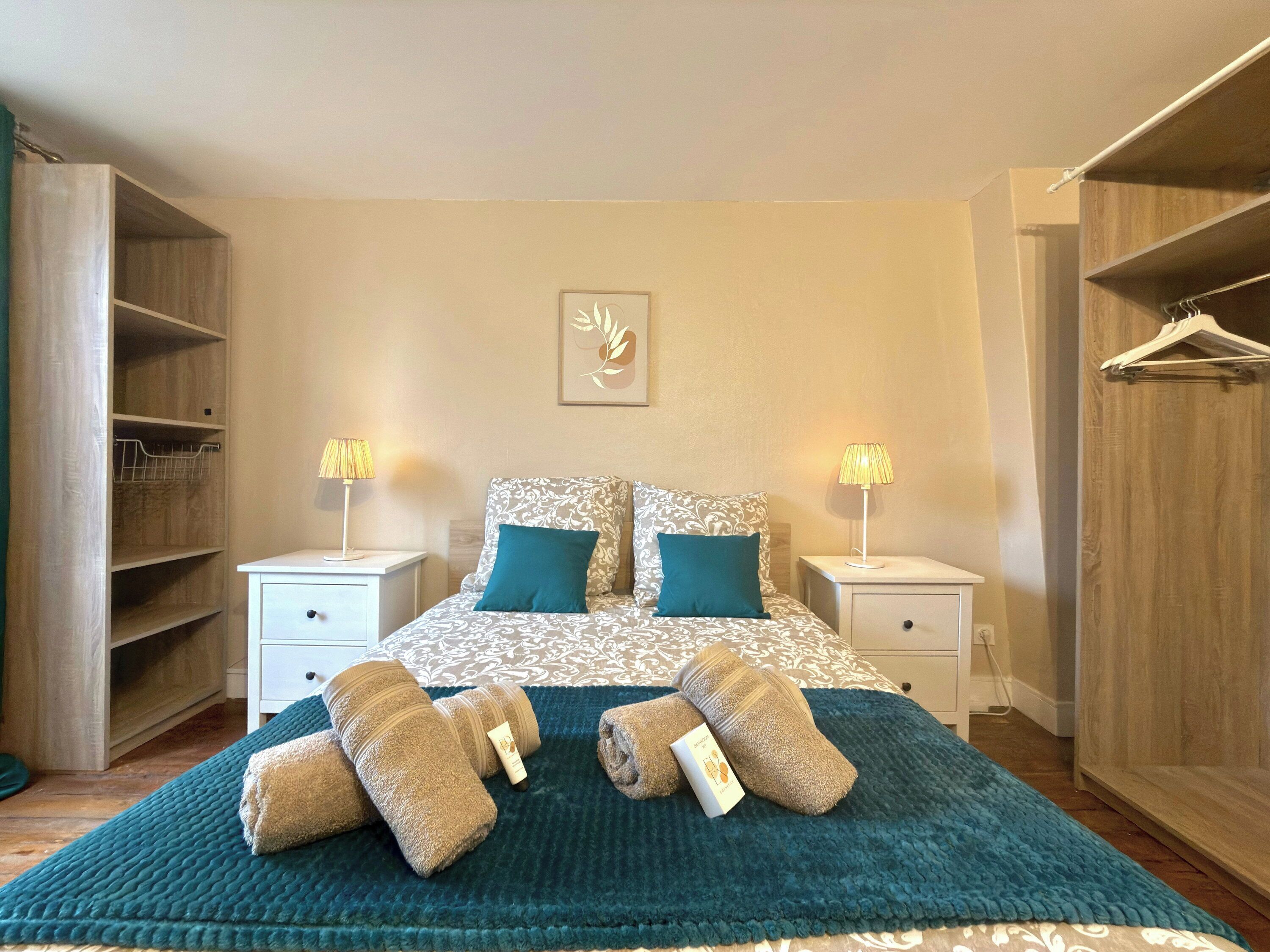 Een slaapkamer met een bed, twee nachtkastjes, een kledingkast en een hangroede.
