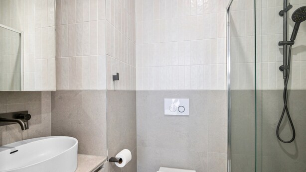 Een moderne badkamer met een wit wastafel, toilet en een douchecabine met glazen wanden.