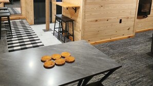 A modern kitchen with wooden walls, a black refrigerator, a wooden table with coasters, and a bulletin board with various notices. - Cozy 1-bedroom bunk style apartment Game Rm/Gym/Stream in historic McDowell! (McDowell)