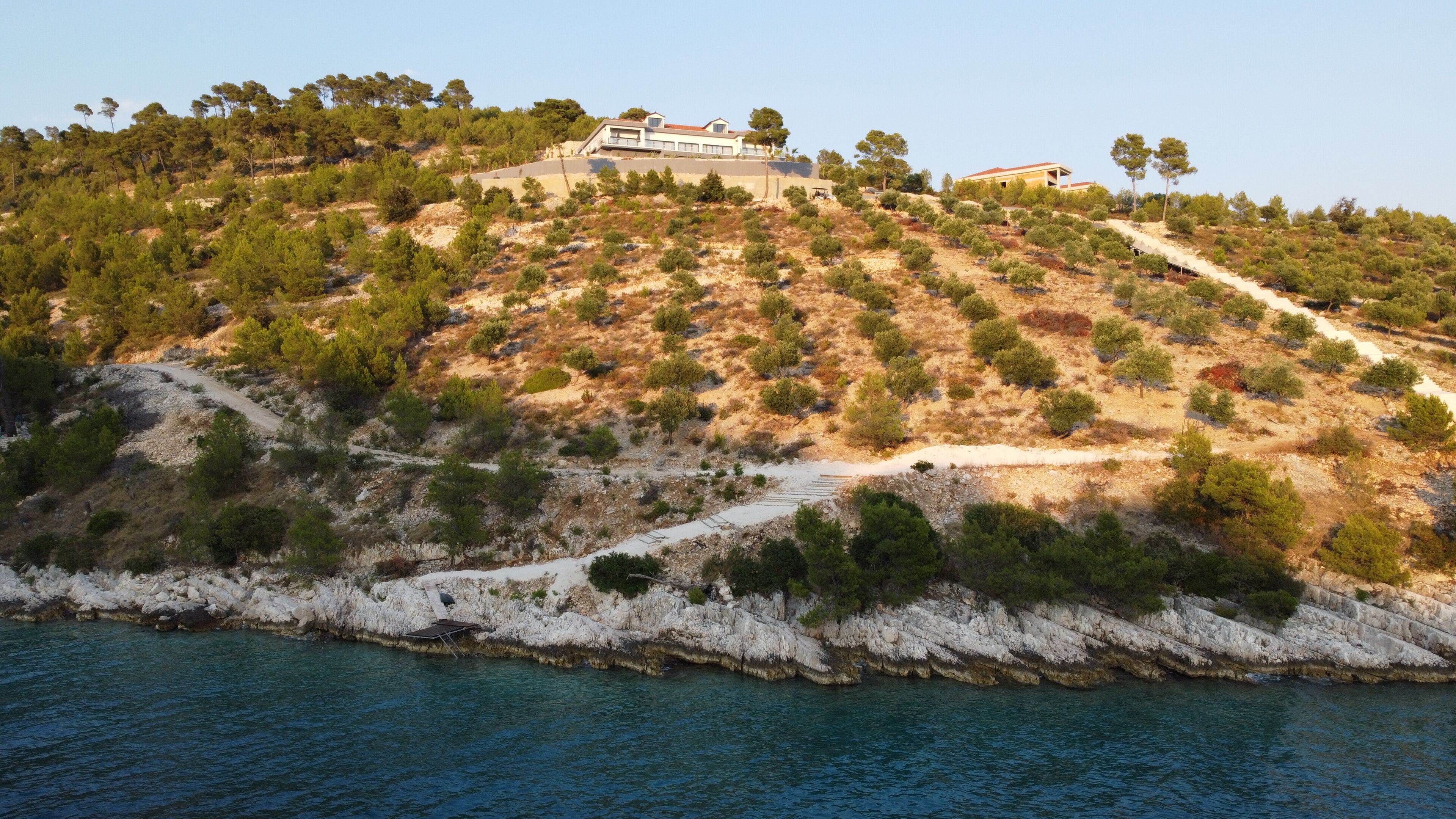 A coastal property with a hillside, a pathway, and a body of water.