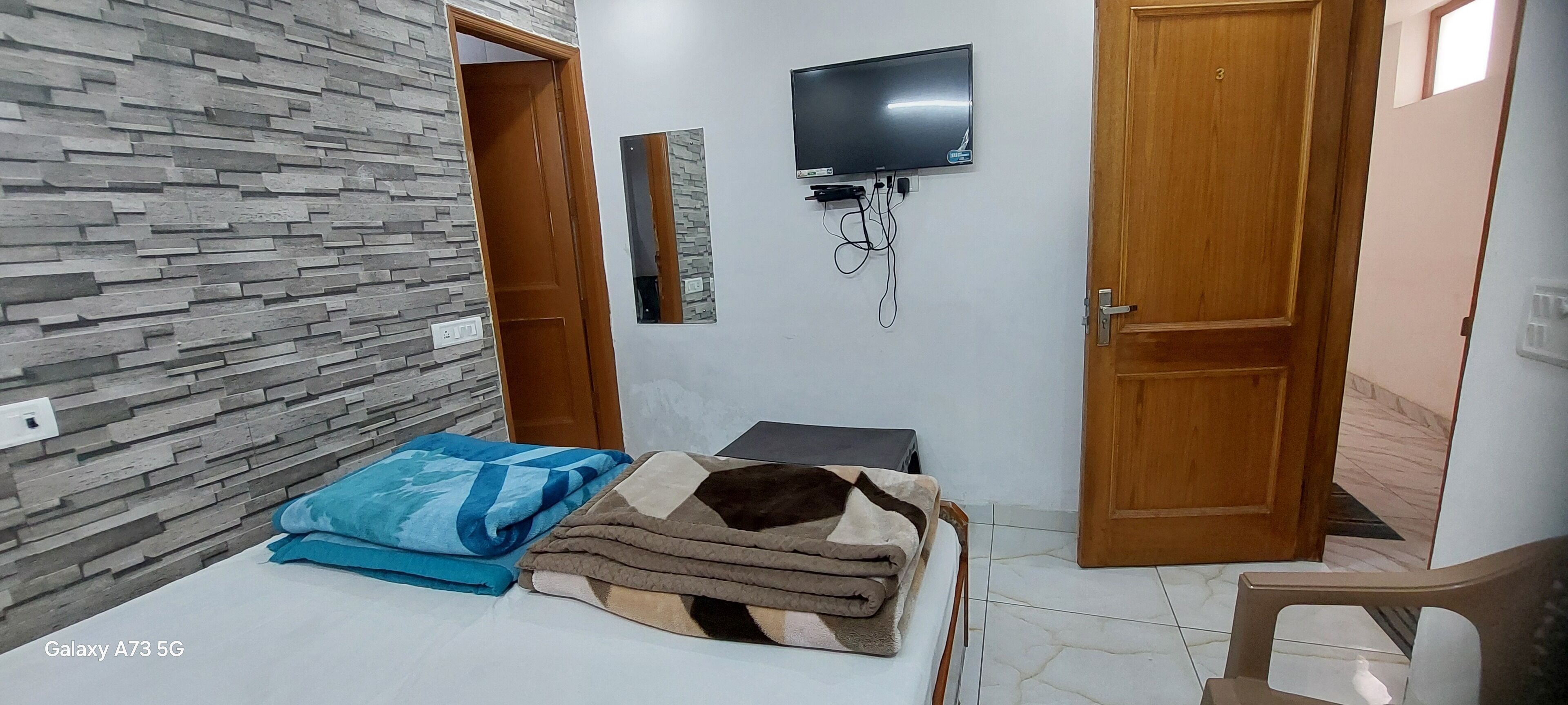 A bedroom with a bed, a TV mounted on the wall, and a mirror.
