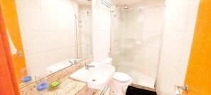Une salle de bain avec une douche à parois de verre, un lavabo et des toilettes.