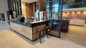 Un espace bar moderne avec un comptoir en bois, des tabourets de bar et un réfrigérateur.