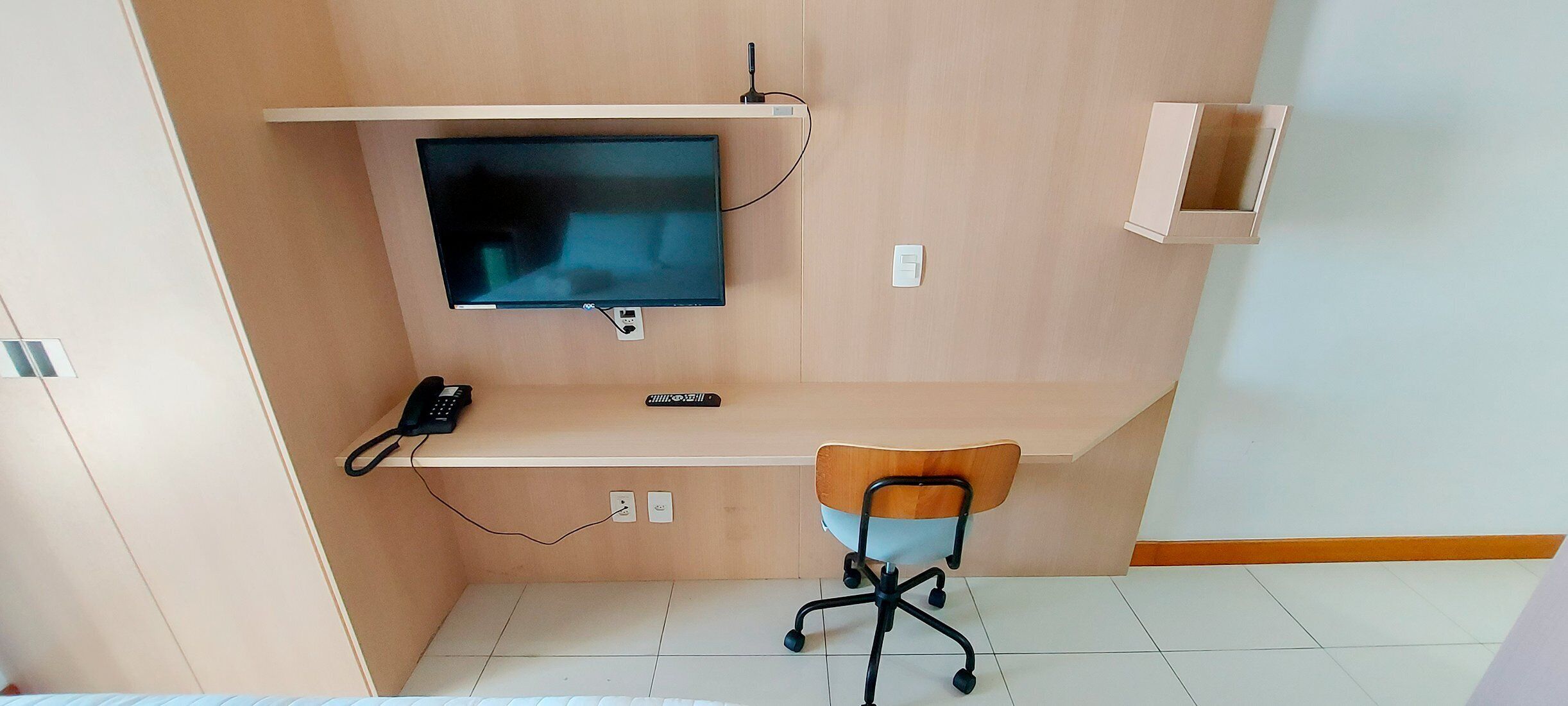 A small office space with a desk, chair, and a mounted flat-screen TV.