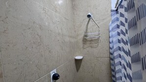 Un baño pequeño con azulejos, cortina de ducha, toallero y jabonera.