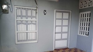 Una habitación con suelo a cuadros, una ventana con barrotes y una puerta con diseño de rejilla.