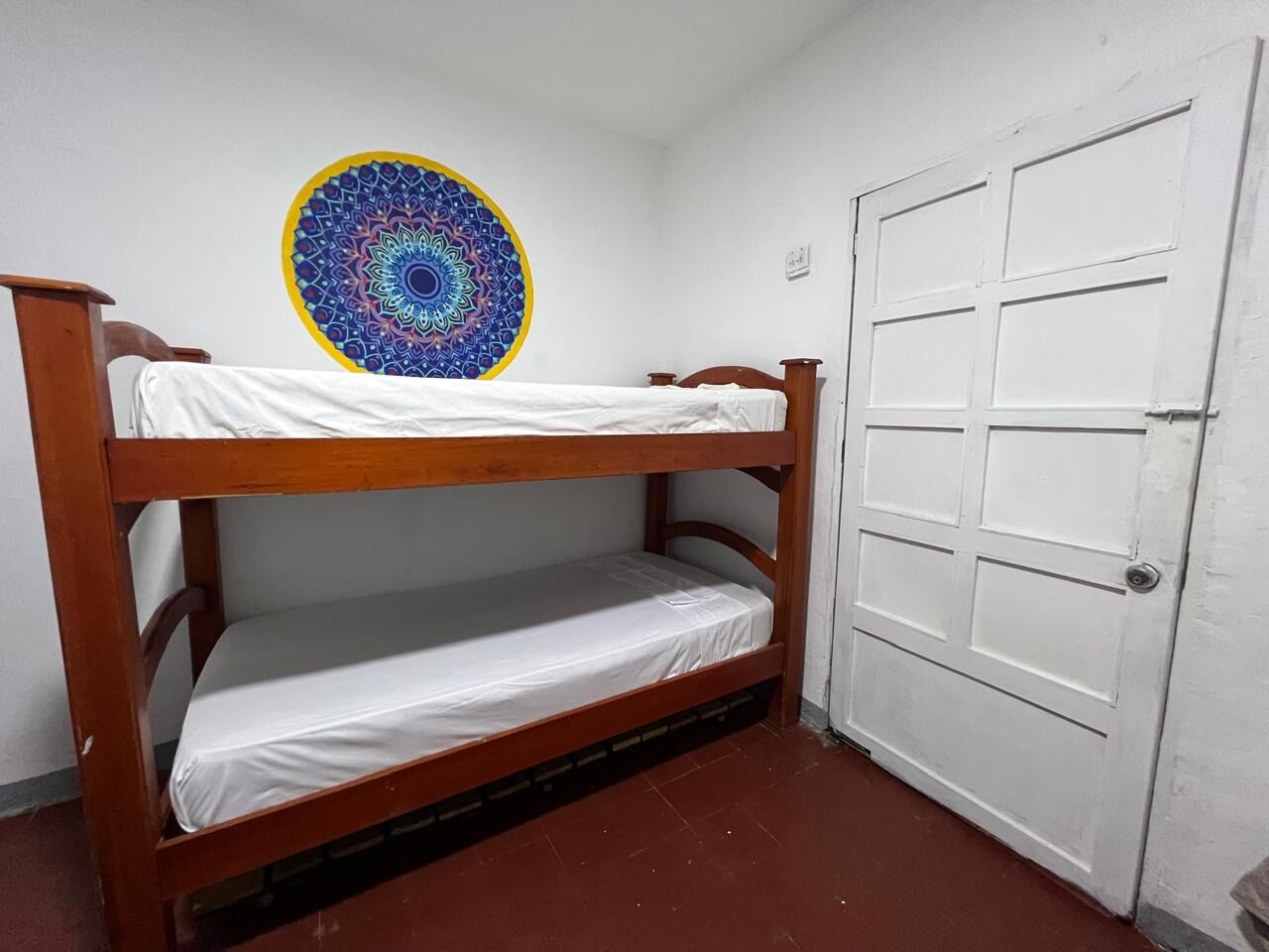 A bunk bed in a room with a white door and a colorful circular wall decoration.