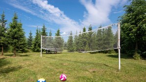 A volleyball net in a grassy area with trees in the background. - Luxurious Holiday Home With Swimming Pool (gmina Dobra)