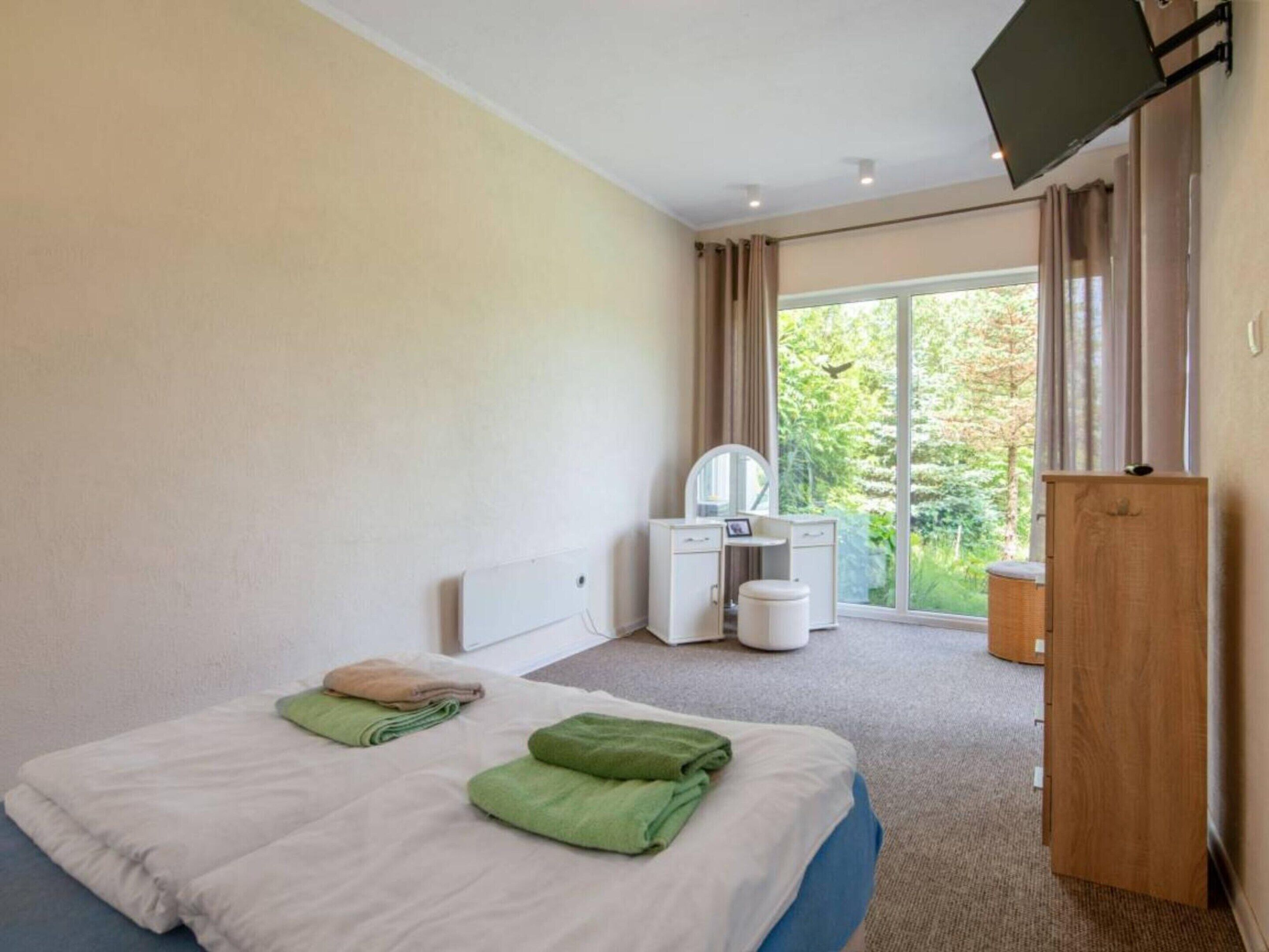 A hotel room with a bed, a desk, a chair, a television, and a view of the outdoors.