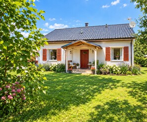 A two-story house with a tiled roof, a front porch with a bench, and a well-maintained garden. - Luxurious Holiday Home With Swimming Pool (gmina Dobra)
