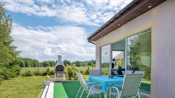 An outdoor patio with a table and chairs, a barbecue grill, and a view of the surrounding landscape. - Luxurious Holiday Home With Swimming Pool (gmina Dobra)