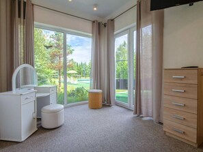 A bedroom with a large window, a vanity with a mirror, a wooden dresser, and a round stool. - Luxurious Holiday Home With Swimming Pool (gmina Dobra)