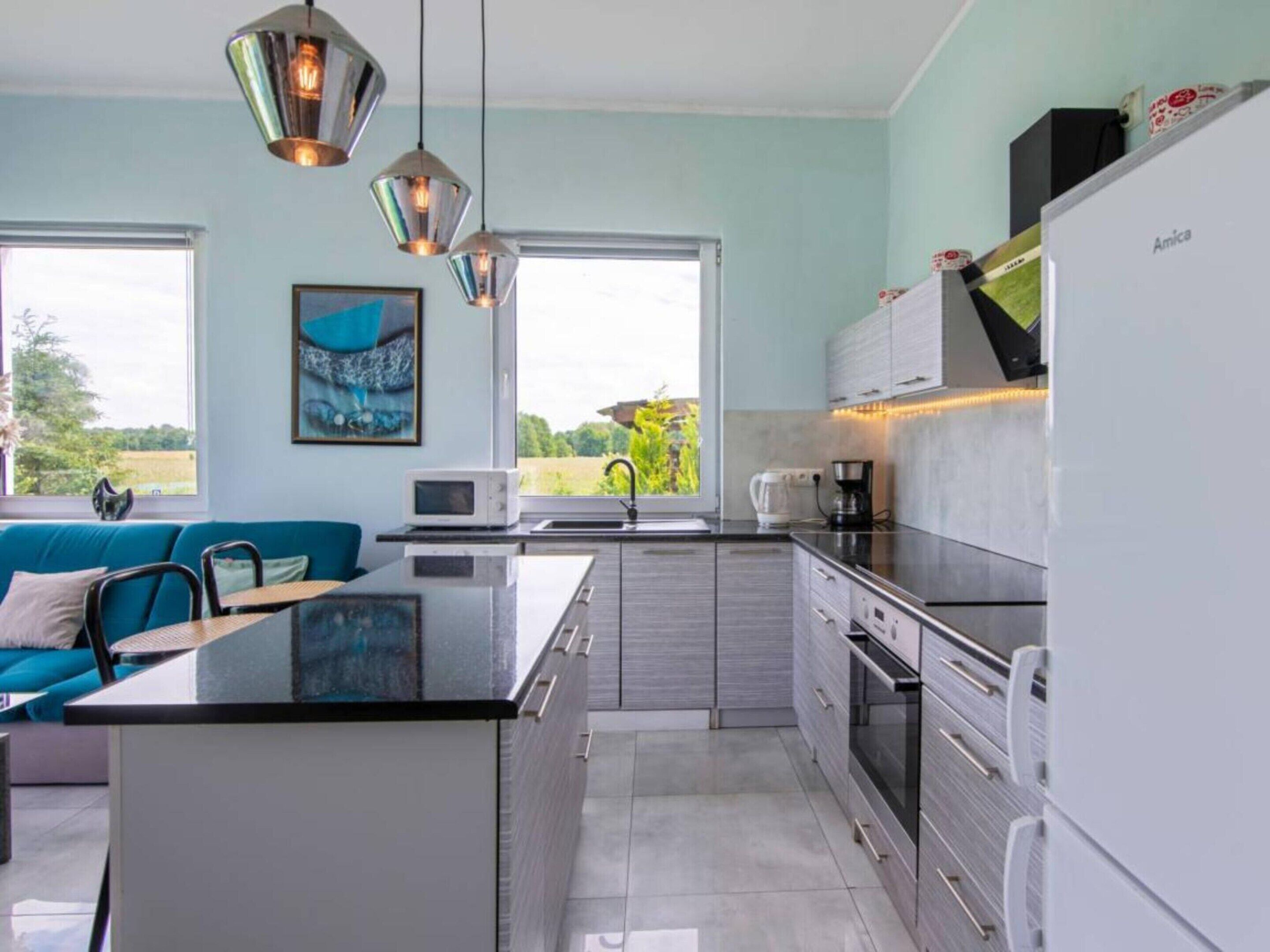 Una cocina moderna con una isla central, electrodomésticos de acero inoxidable y vistas al exterior.